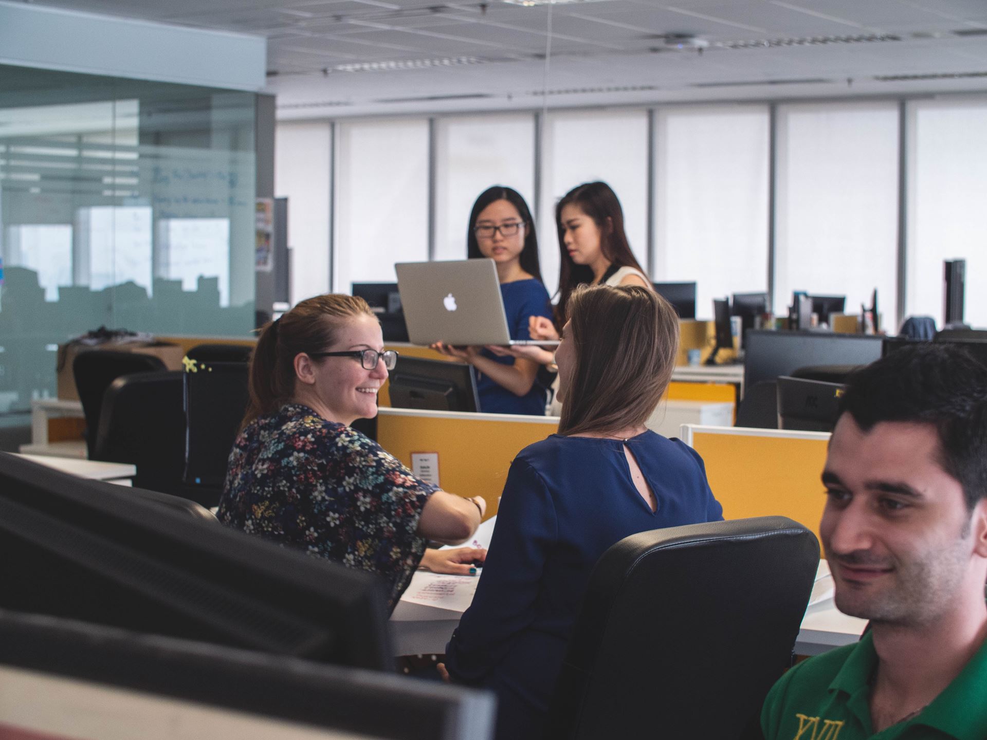 a group of people sitting at a table looking at a laptop